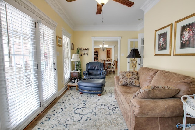 living room with wood finished floors, ornamental molding, and ceiling fan with notable chandelier