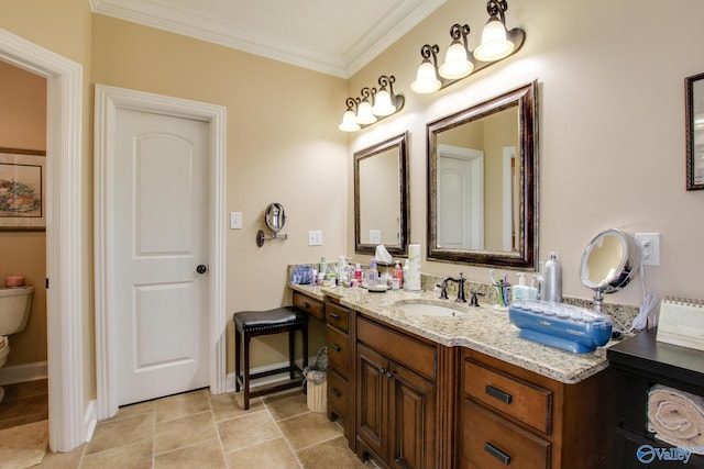 bathroom with toilet, vanity, crown molding, and baseboards