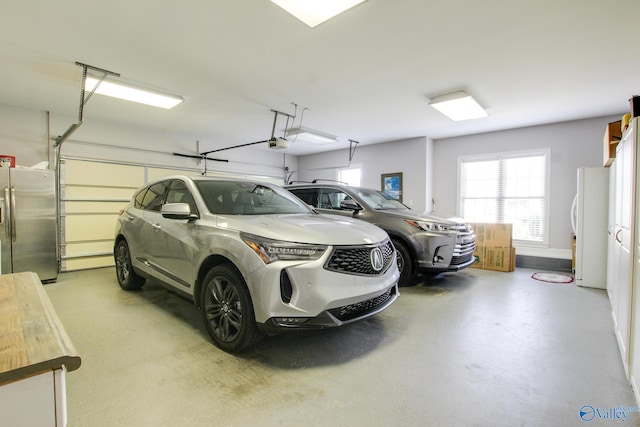 garage with a garage door opener, stainless steel refrigerator with ice dispenser, and freestanding refrigerator