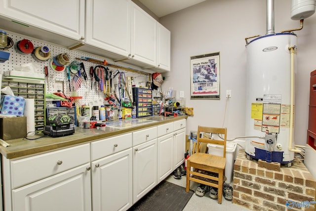 kitchen with gas water heater, white cabinets, and light countertops