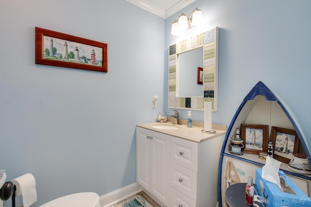 half bathroom with baseboards, toilet, ornamental molding, and vanity