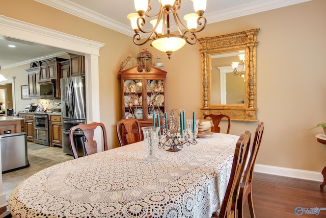 dining space featuring light wood-style flooring, ornamental molding, baseboards, and a chandelier