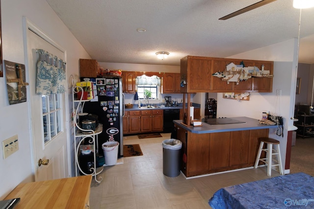 kitchen with lofted ceiling, a textured ceiling, kitchen peninsula, ceiling fan, and black appliances