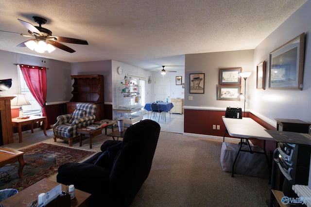 carpeted living room featuring ceiling fan and a textured ceiling