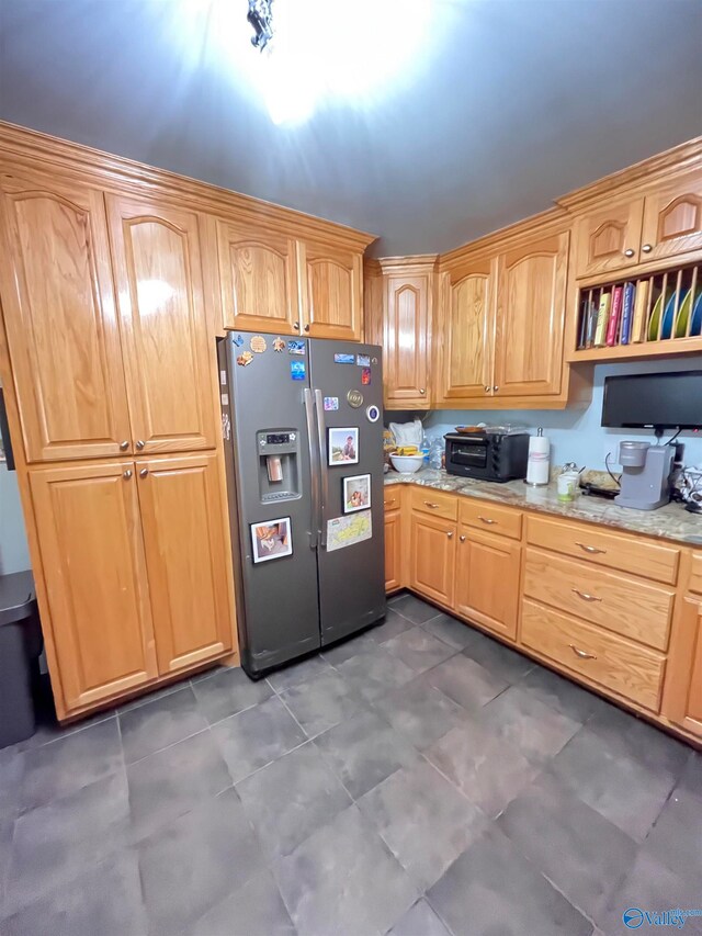 kitchen featuring stainless steel refrigerator with ice dispenser and light stone counters