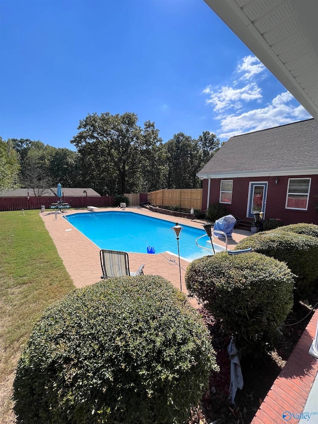 view of swimming pool featuring a yard, a diving board, and a patio area