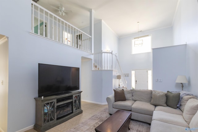 living area featuring stairway, baseboards, a towering ceiling, and crown molding