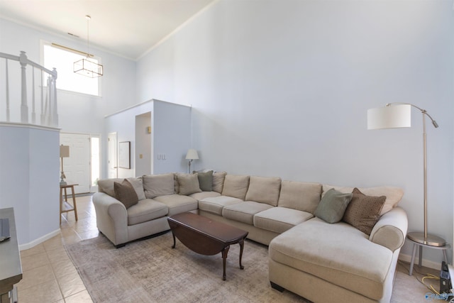 living area featuring light tile patterned floors, baseboards, a high ceiling, and ornamental molding