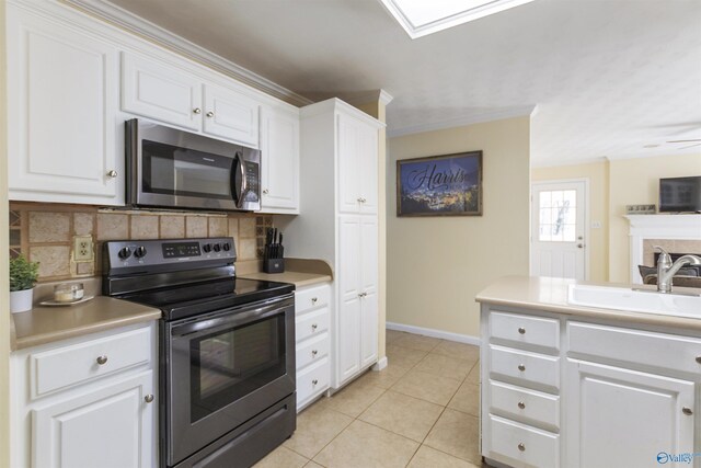 kitchen featuring light tile patterned flooring, a sink, appliances with stainless steel finishes, white cabinetry, and tasteful backsplash