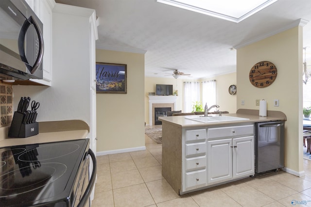 kitchen featuring ornamental molding, a tiled fireplace, a sink, black microwave, and dishwasher