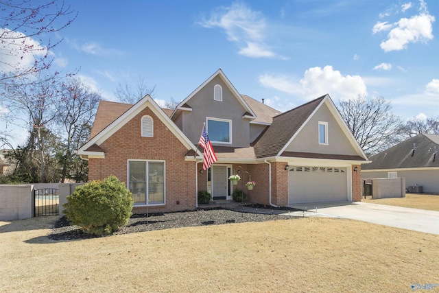 traditional-style home featuring a front yard, a gate, fence, concrete driveway, and brick siding