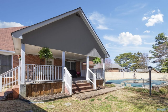 exterior space with covered porch, a fenced in pool, brick siding, and a fenced backyard