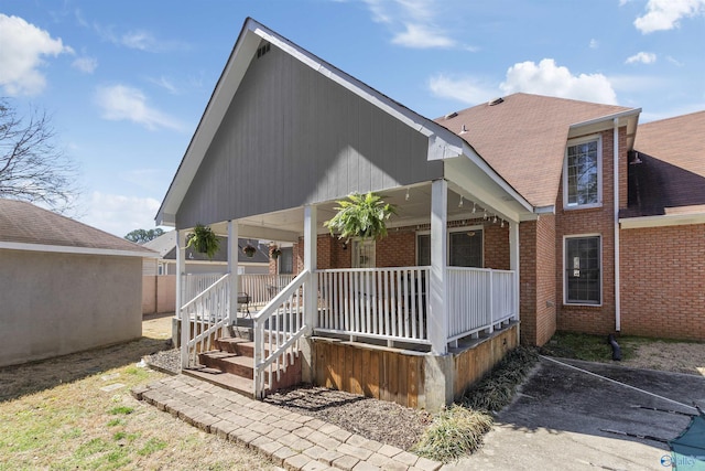 rear view of house with brick siding and covered porch