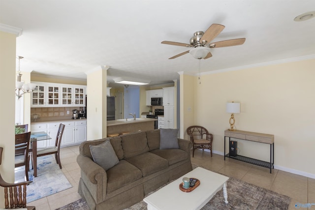 living area with light tile patterned floors, a ceiling fan, baseboards, and ornamental molding