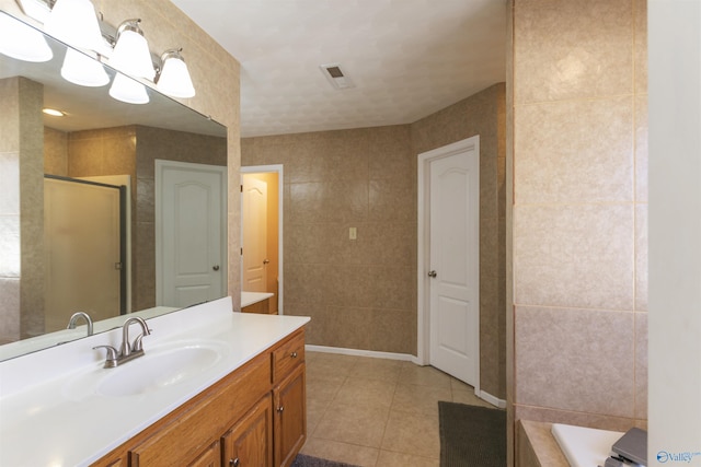 full bathroom with visible vents, a shower with door, tile walls, tile patterned flooring, and vanity