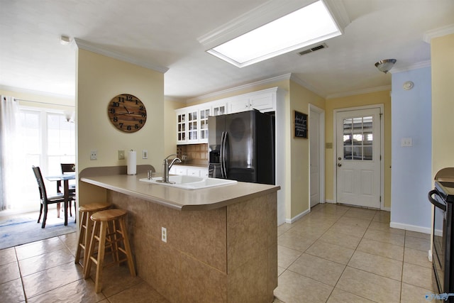 kitchen with visible vents, ornamental molding, a sink, black appliances, and a kitchen bar