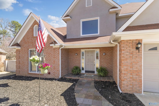 view of front of home with a garage, brick siding, and stucco siding