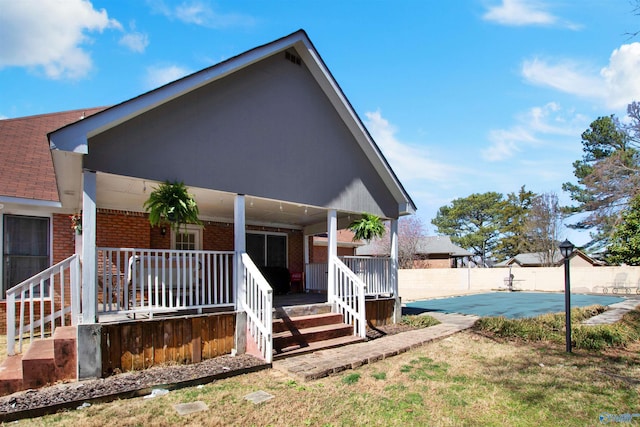 view of front of house with a fenced in pool, brick siding, a porch, and fence