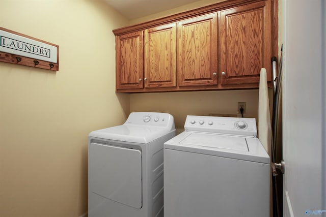 clothes washing area featuring washing machine and clothes dryer and cabinet space