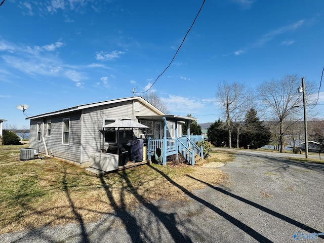 view of front of house with gravel driveway, a front yard, and central AC unit