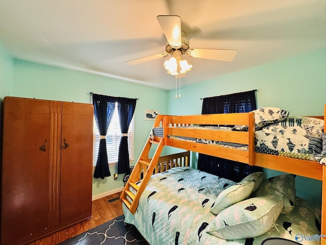 bedroom with baseboards, visible vents, wood finished floors, and a ceiling fan