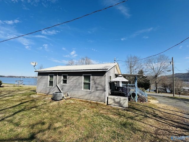 view of property exterior featuring cooling unit, a lawn, and metal roof