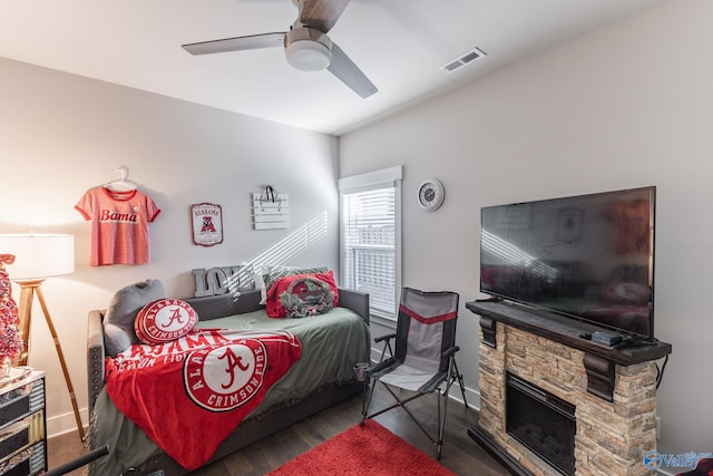 bedroom featuring a fireplace, dark hardwood / wood-style flooring, and ceiling fan