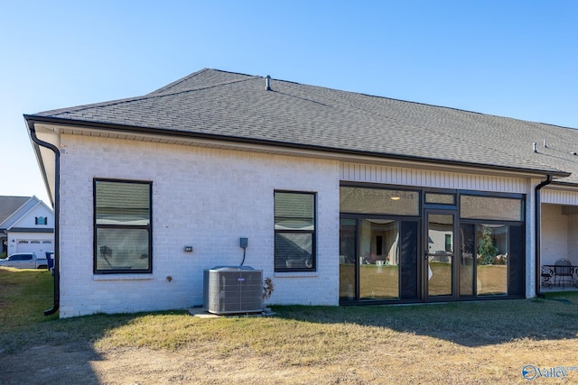 rear view of house with a yard, central AC, and a sunroom