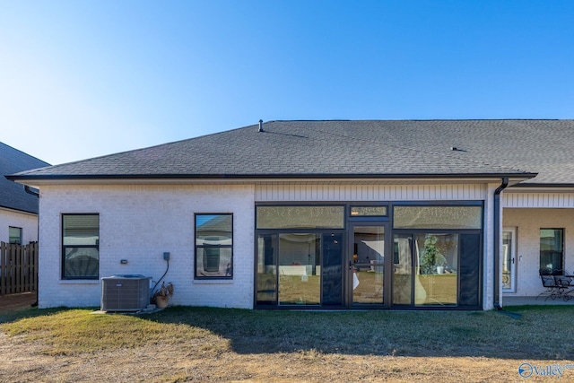 back of house with a sunroom, a lawn, and central AC