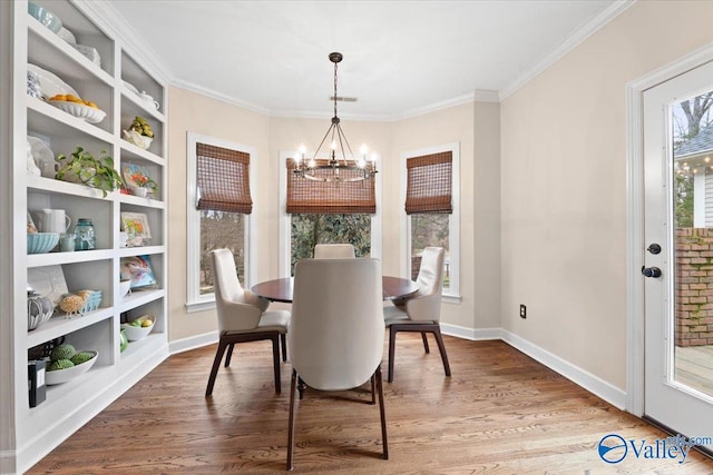 dining space with ornamental molding, baseboards, an inviting chandelier, and wood finished floors