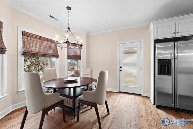 dining room with crown molding, a notable chandelier, visible vents, light wood-style floors, and baseboards