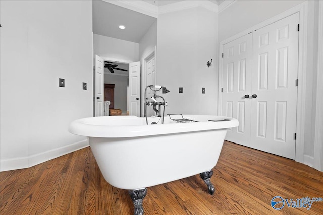 bathroom with a freestanding tub, baseboards, and wood finished floors