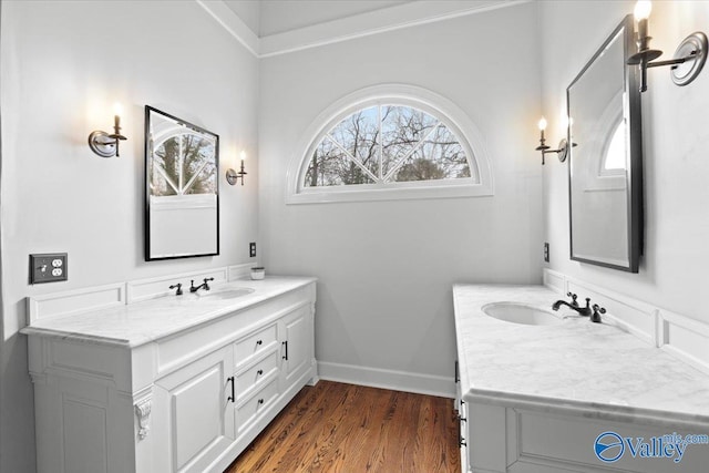 bathroom with two vanities, a sink, baseboards, and wood finished floors