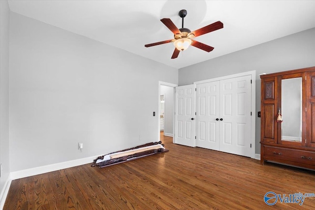 unfurnished bedroom featuring a ceiling fan, a closet, baseboards, and wood finished floors