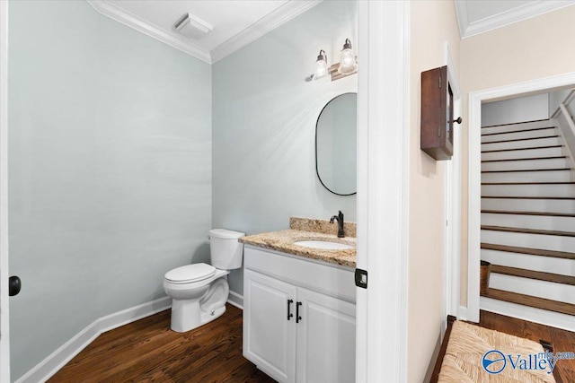 bathroom featuring crown molding, toilet, vanity, wood finished floors, and baseboards