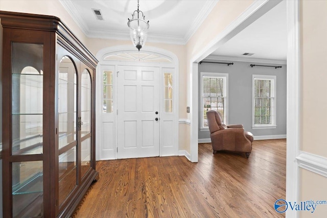 entryway with ornamental molding, visible vents, baseboards, and wood finished floors