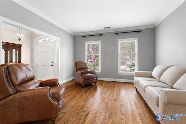 living room featuring ornamental molding, visible vents, baseboards, and wood finished floors