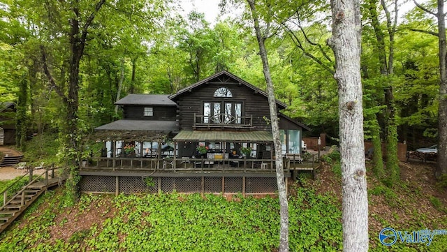 rear view of property with stairs, log exterior, french doors, and a view of trees