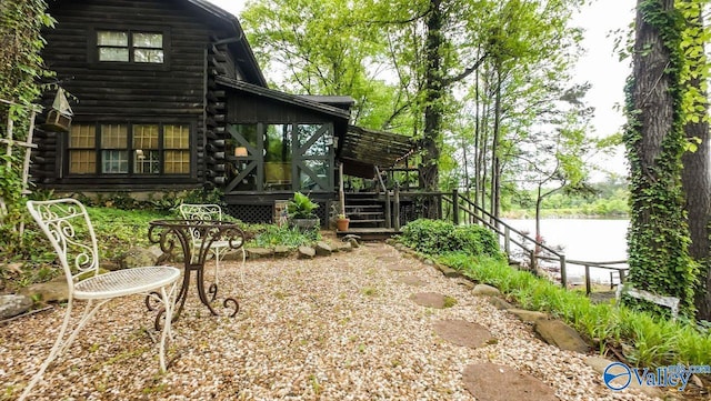 rear view of property featuring log exterior and a deck with water view