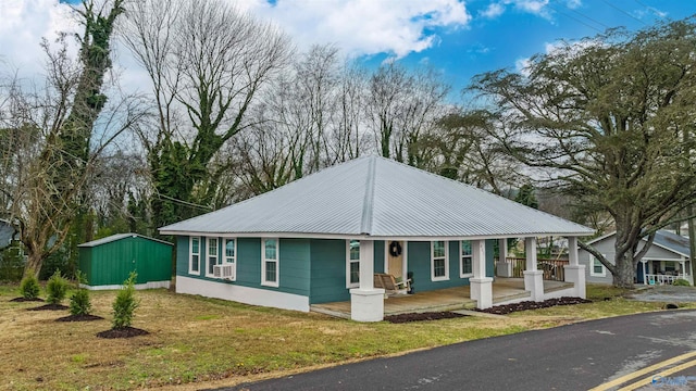 view of front of property featuring cooling unit, a front lawn, a porch, and a storage shed