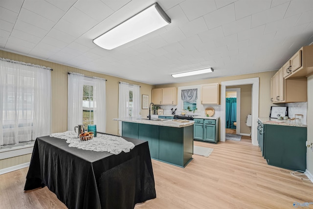 kitchen featuring sink, light wood-type flooring, an island with sink, and light brown cabinetry