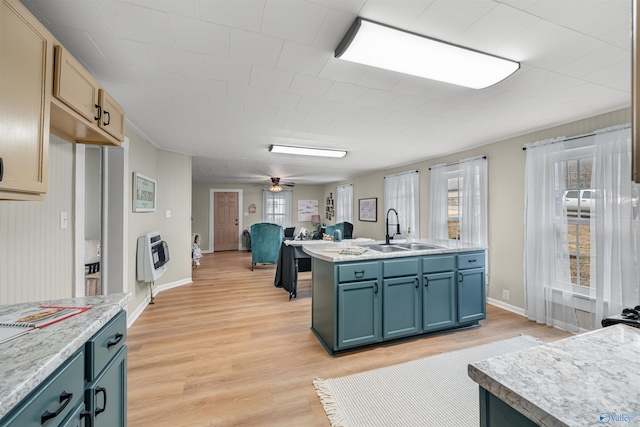 kitchen with ceiling fan, blue cabinets, sink, and light hardwood / wood-style flooring