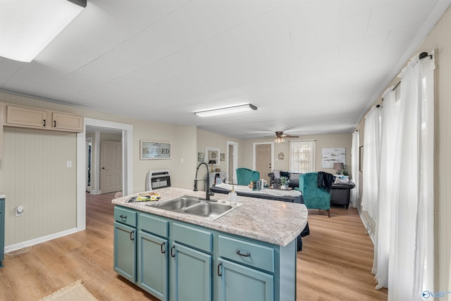 kitchen with ceiling fan, sink, an island with sink, and light hardwood / wood-style flooring