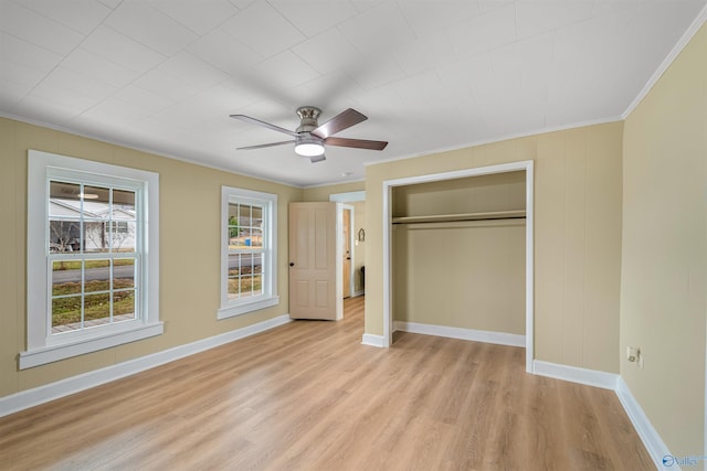 unfurnished bedroom featuring ceiling fan, light wood-type flooring, crown molding, and a closet