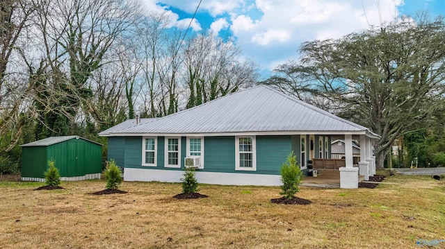 view of front facade featuring a porch, cooling unit, a front yard, and a storage shed