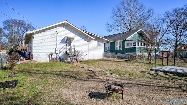 view of side of property featuring an outdoor fire pit and a yard