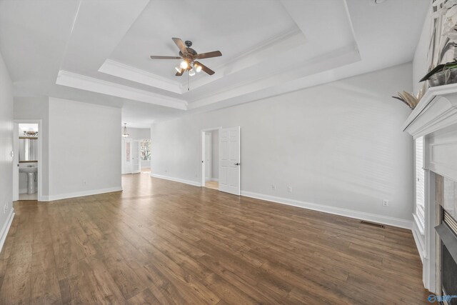 unfurnished living room with dark wood-type flooring, ceiling fan, and a raised ceiling