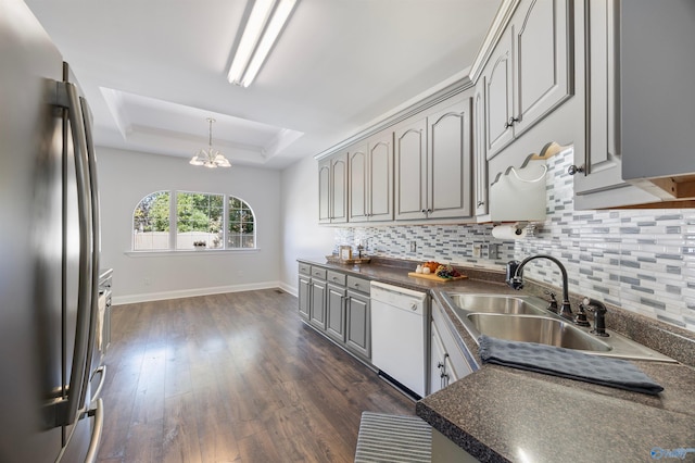 kitchen featuring stainless steel fridge, a raised ceiling, dark hardwood / wood-style flooring, white dishwasher, and gray cabinets