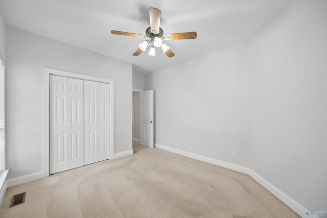 unfurnished bedroom with a closet, light colored carpet, and ceiling fan