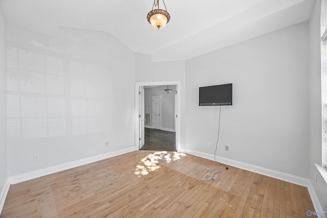 unfurnished room with hardwood / wood-style floors and vaulted ceiling